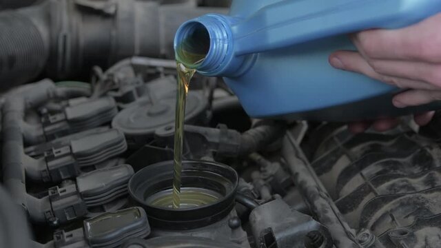 Pouring engine new clean synthetic oil into the engine.Oil change in auto.