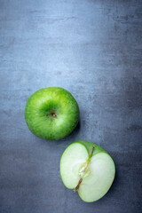 Fresh green apple and a sliced apple on a gray stone, free space for edits