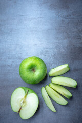 Fresh green apple and a sliced apple on a gray stone, free space for edits