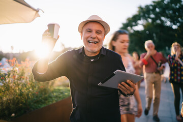 Half length portrait of excited male tourist with takeaway cup and digital tablet for travel...