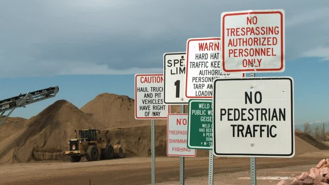 Close-up of warning signs, in the background a bulldozer moving dirt
