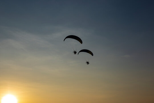 Paragliders flying with a paramotors during beautiful sunset