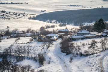 Wonderful winter landscape with a small village nestled between snow-covered hills