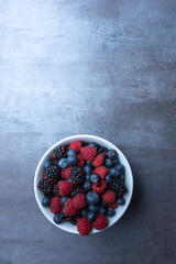 mixed berries in a bowl, gray background, seen from above
