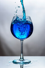 Blue water in translucent glass on white background.