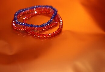 Three Blue and red color beaded crystal hand jewellery or bracelets isolated on beautiful orange or golden shiny background