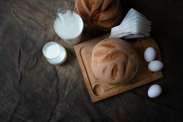 Still life of freshly baked milk bread with eggs and bottle of milk.