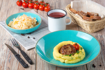 plate with mashed potato and meat with pickles in bowl and milk glass on wooden background, close view 