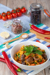 plate with salad of meat pieces and vegetables on wooden background, close view 
