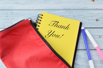 Top view of pen colors, pencil case and notebook written with text THANK YOU!.
