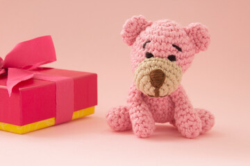 Small crochet bear in pink with a gift box on the back. Pink color. Love concept. Valentine´s day.