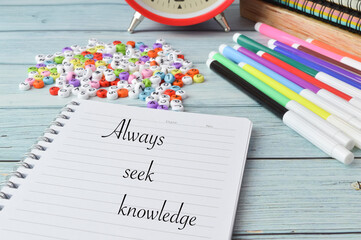 Selective focus of colorful alphabet beads, colors,clock and notebooks written with text ALWAYS SEEK KNOWLEDGE. Education concept.
