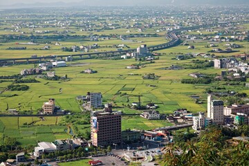 A curved highway through the green rice fields with houses scattered throughout the plain in Yilan, Taiwan ~ Aerial view of National Freeway No.5, Taipei-Ilan Section in Ilan, Taiwan, Asia