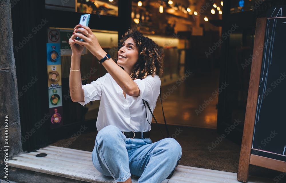 Aufkleber happy caucaisan hipster girl photographing city while resting near doorway using cellphone device fo