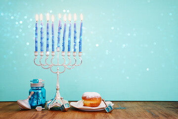 Image of jewish holiday Hanukkah with menorah (traditional Candelabra), donut and wooden dreidel...