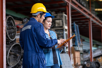 Confident Asia engineer woman worker wears a safety helmet holding clipboard and discusses with a...