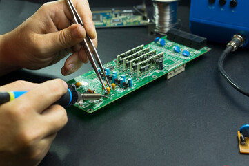 An electronics technician repairs components of a computer circuit board. Complex work with a...