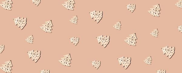 New Year's composition. Trendy Christmas pattern from wooden Christmas trees of different sizes with a hard shadow on a sand-colored background. Flat lay, top view. Creative minimal christmas art.
