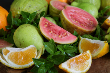sliced and whole guava and tangerine fruits with Basil leaves