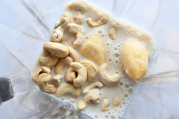 Superfood, vegan ingredients photographed on a high-key background, include bananas, blueberries, kale, soy milk, flaxseed milk, peanut butter, pumpkin seeds and salt.
