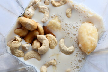 Superfood, vegan ingredients photographed on a high-key background, include bananas, blueberries, kale, soy milk, flaxseed milk, peanut butter, pumpkin seeds and salt.
