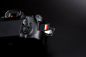 DSLR camera body and memory card in slot on black background