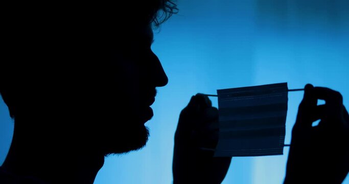Silhouette di una persona che si mette la mascherina