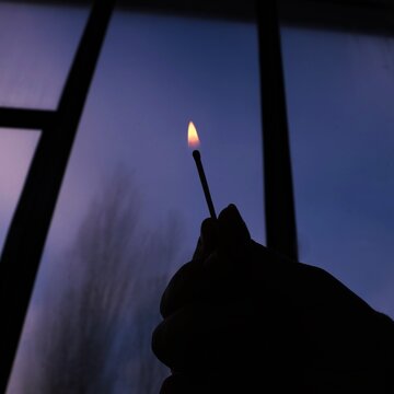 Cropped Hand Holding Matchstick By Window