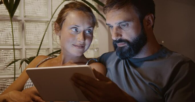 Young married couple in love watching ultrasound image of future child on electronic tablet at home. Concept of family, birth, life, love, gental parenthood.
