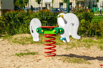 Kolorowa, drewniana huśtawka na sprężynie w kształcie słonia na placu zabaw - obrazy, fototapety, plakaty