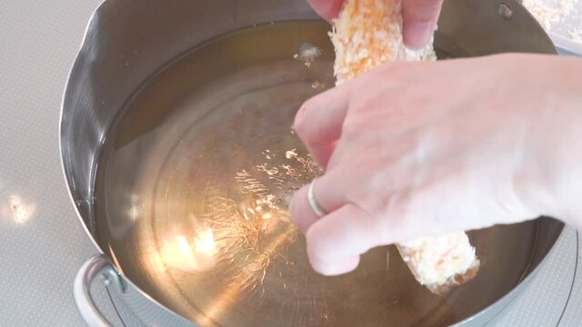 豚カツを鍋の油で揚げているシーン