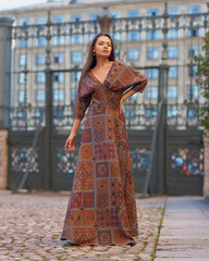 Elegant woman with longhair in brown dress walking at street in the city on a summer day