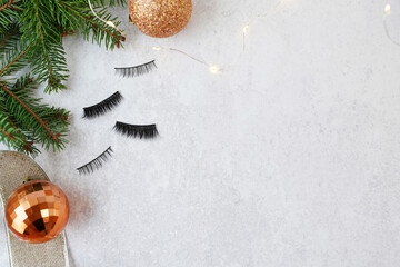 false eyelashes with christmas decorations on gray background, copy space