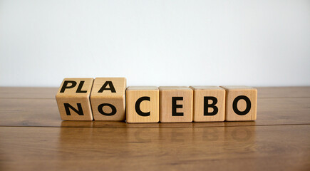 Nocebo or placebo. Turned cubes and changed the word 'placebo' to 'nocebo', or vice versa. Beautiful wooden table, white background, copy space. Medical and science concept.