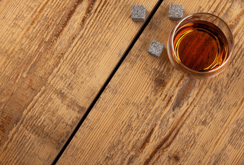 Szklanka z napojem na tle jasnych, starych desek. Kamienne kostki ułożone w pobliżu szklanki. © Mikołaj Rychter