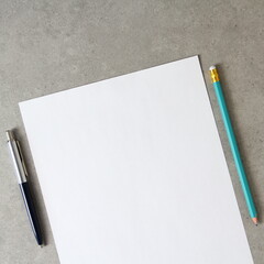 Template of white paper with a ballpoint pen and simple pencil on light grey concrete background. Concept of new idea, business plan and strategy,  empty space for text