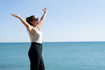 Close-up portrait of smiling young woman celebrating with open arms on ocean summer background.People success , freedom and success lifestyle concept.Copy space for text.