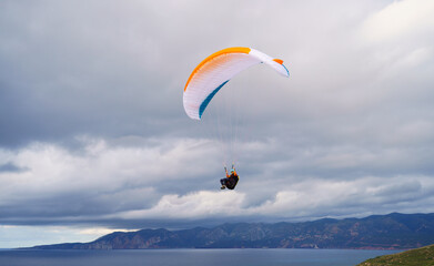 Paragliding flying over the sea in the mountains in southern Sardinia
