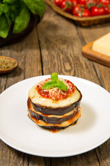Baked eggplant mozzarella and parmesan stacks with ingredients on a rustic wooden table. Close up. Selected focus.
