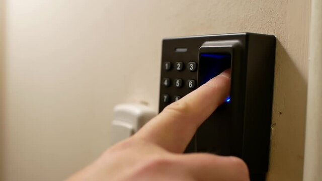Close-up video of a man puts his finger on the fingerprint sensor to open doors. A man opens a door lock using a biometric sensor.