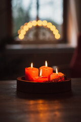 advent wreath with burning red candles standing on wooden table in living room with candle arch in...