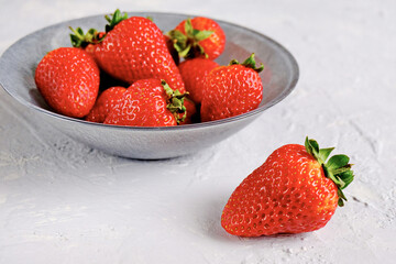 A plate of beautiful strawberries isolated on grey concrete. Tasty and healthy diet. Copy space.