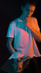 Fototapeta premium a young guy holds a mirror in his hand, looks at his reflection, a yellow and blue vet illuminates a man