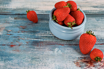 Red strawberries in bowl on turquoise wooden background.  Tasty and healthy diet. Wonderful breakfast. Copy space.