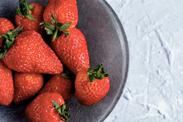 A plate of beautiful strawberries isolated on grey concrete. Tasty and healthy diet. Copy space. Close up.