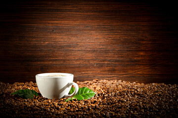 Coffee beans on a brown board with a green leaf