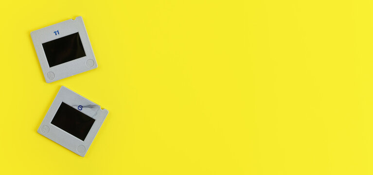 Two diapositive photo slides on yellow table, view from above, space for text right side, retro photography concept