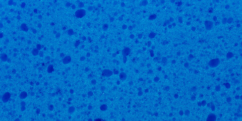 The intense blue surface of an artificial sponge, with many holes. Useful texture or backdrop.
