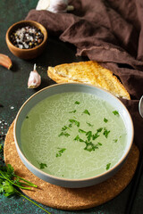 Healthy lunch. Hot rich meat broth (bouillon) with herbs and garlic croutons on a dark slate countertop.