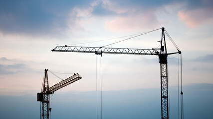 Fototapeta premium Construction banner. Cranes in front of sunset sky. Building concept. Copy space